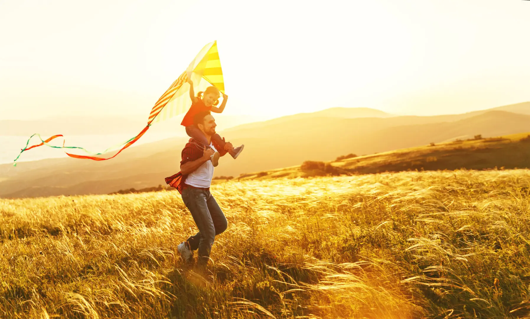 A woman holding onto a kite in the middle of a field.