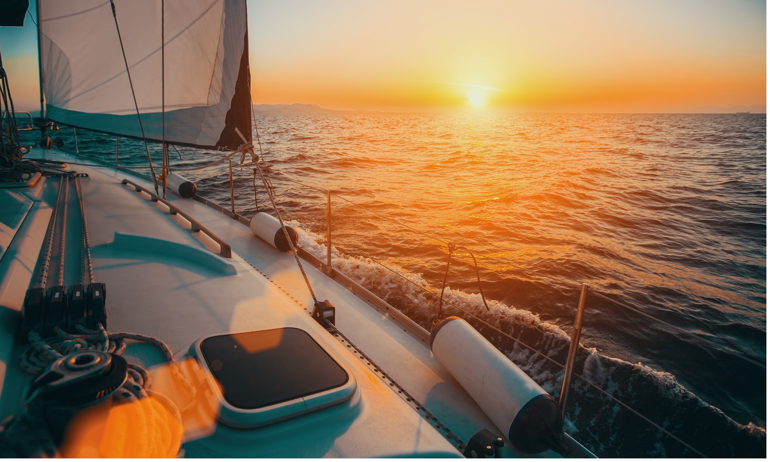 A boat is sailing on the ocean at sunset.